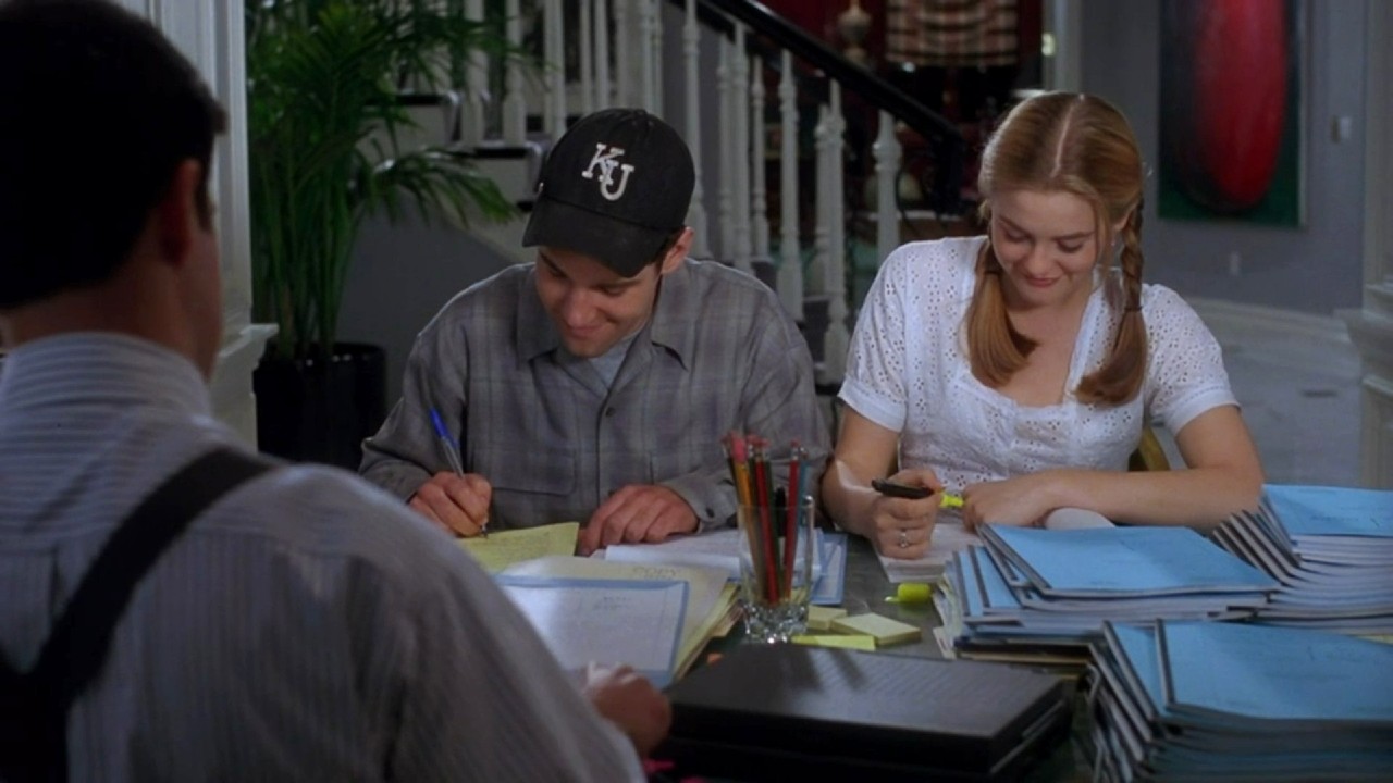 Paul Rudd and Alicia Silverstone smiling looking down in Clueless.