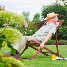 Gardener sleeping in a lawn chair because he has low-maintenance front yard landscaping