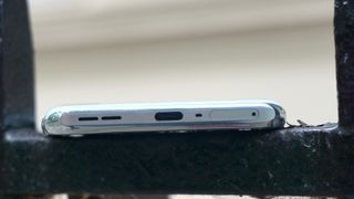 Mobiltelefonen OnePlus 10T liggende slik at ladeporten vender mot betrakteren.