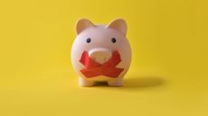 A piggy bank has red tape across its mouth.