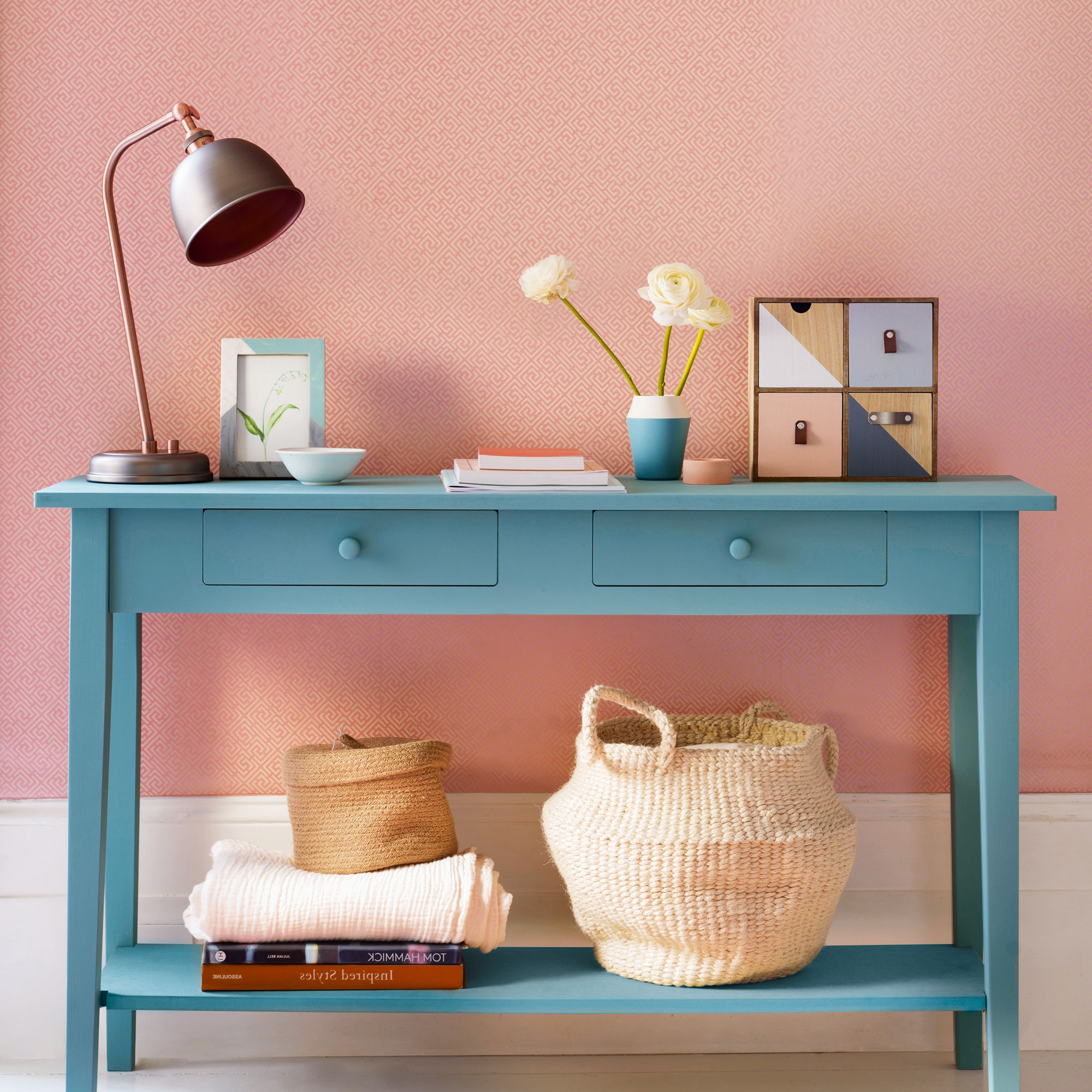 Pink wall with blue console table and table lamp