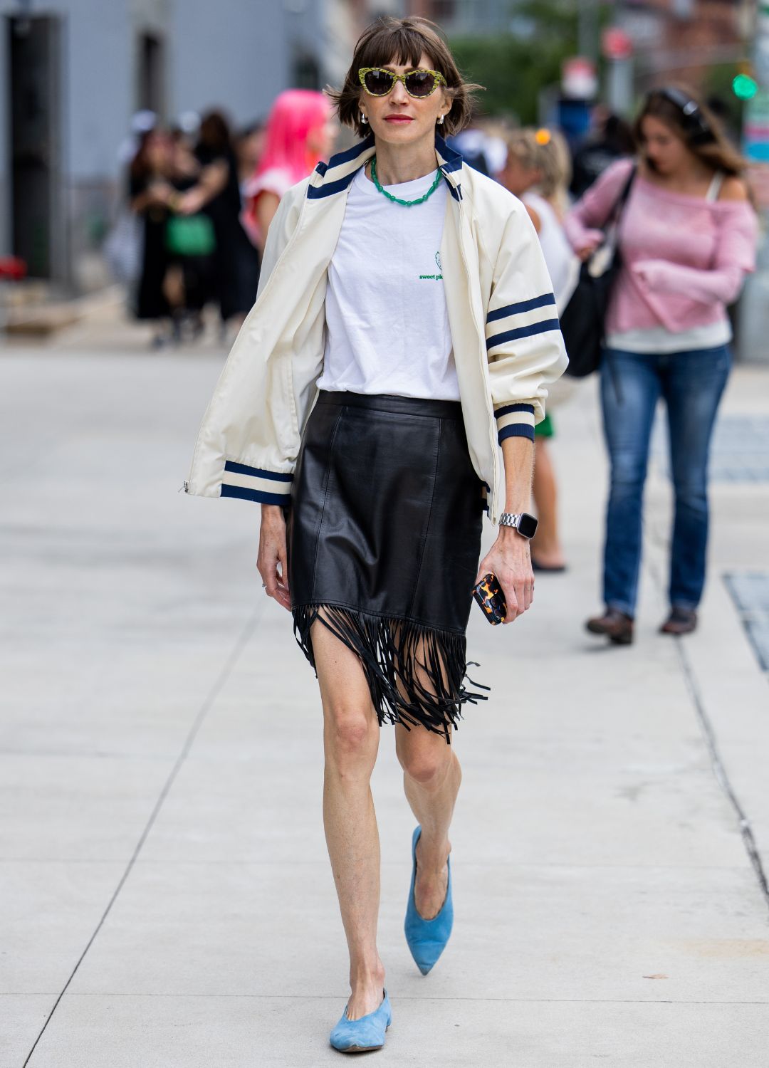 A guest wears black skirt with fringes, beige jacket, white shirt outside Area during New York Fashion Week on September 06, 2024 in New York City