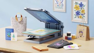xTool Screen Printer; a laser printing machine on a wooden table surrounded by bags and cards