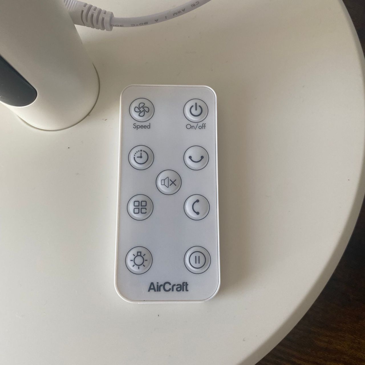 Remote control of the AirCraft LUME Quiet Air Circulator Fan positioned on the base of the fan