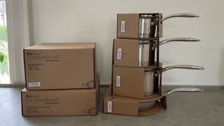 The ProCook Professional Stainless Steel Uncoated Cookware Set on a counter with cardboard packed around them