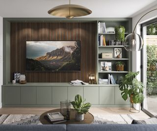 tv mounted on wall panelling in built in green bespoke media wall in living room