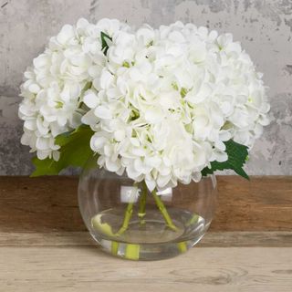 artificial white hydrangeas in a globe vase