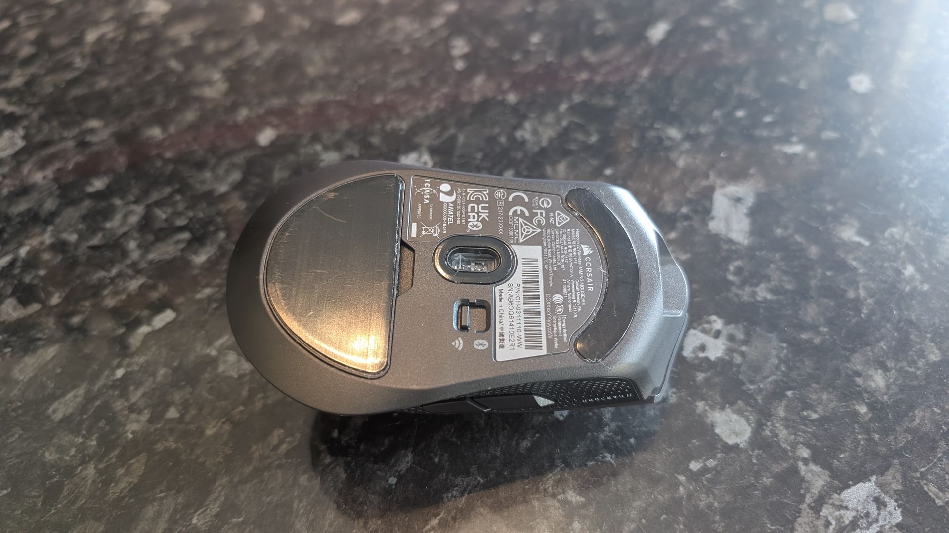 The Corsair Harpoon V2 Wireless gaming mouse pictured on a dark marble worktop.