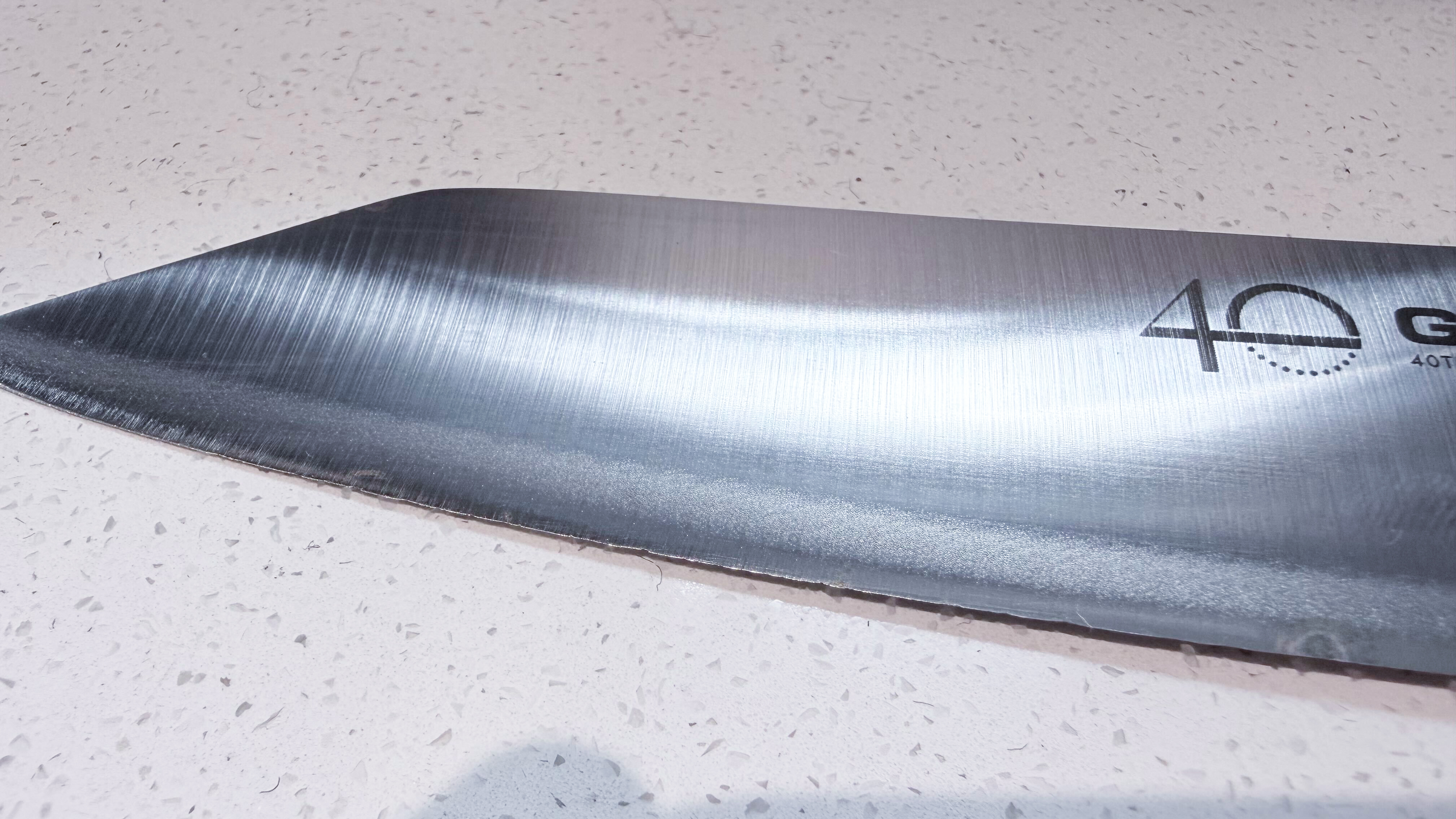 An image showing the edge of a Global chef's knife, with knicks and dents in the edge