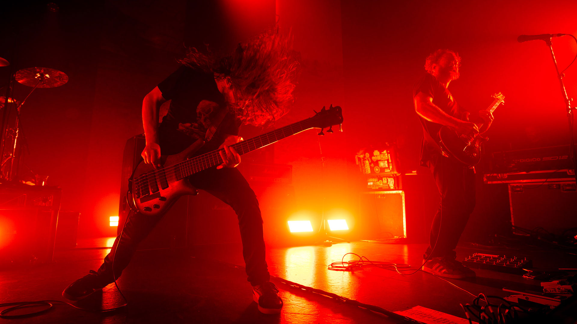 Karnivool bassist Jon Stockman and guitarist Mark Hosking onstage with a red backlight