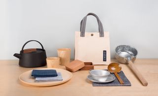 Beech table with wooden plate and cups and cast kettle with linen bag