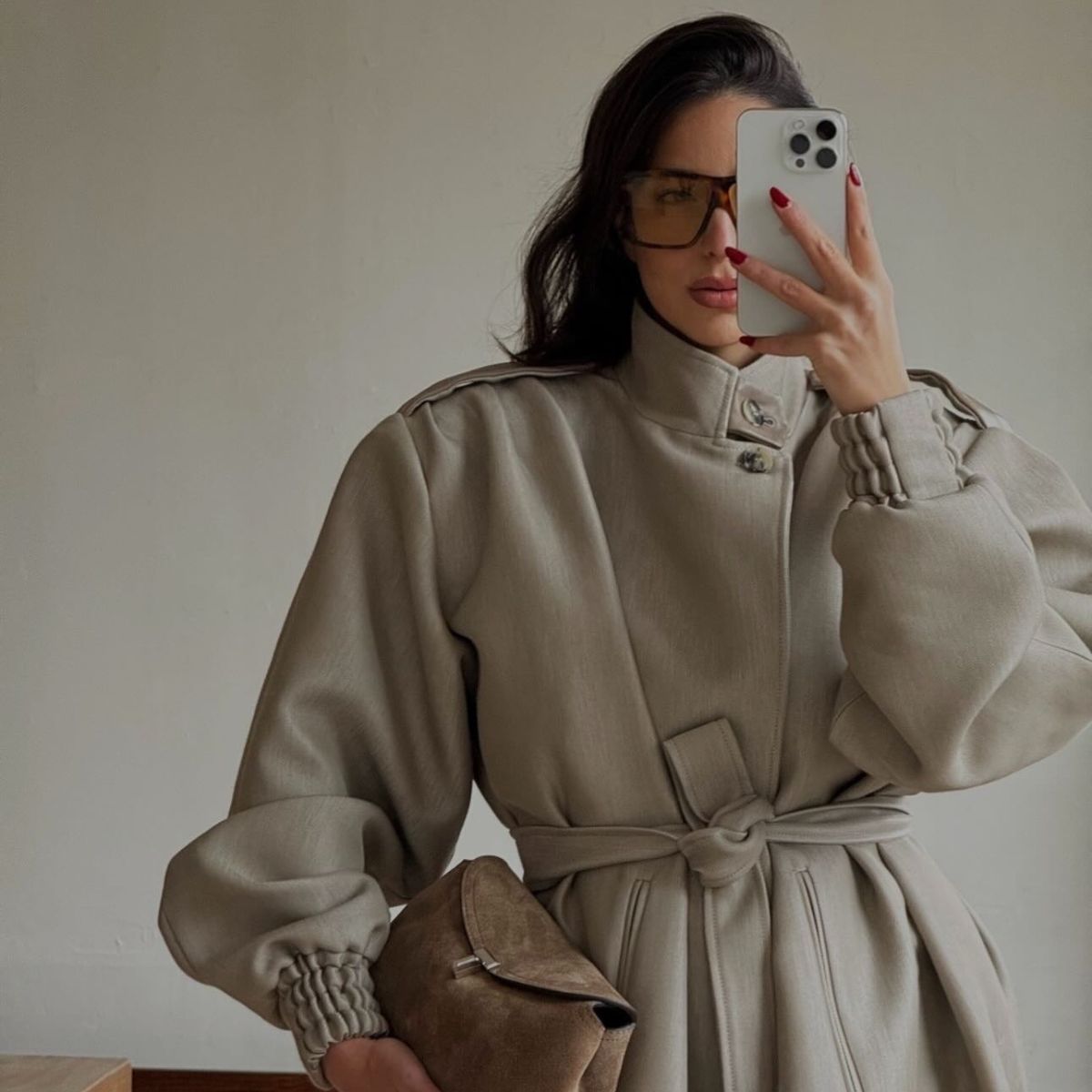 A picture of @bettinalooney taking a mirror selfie in a beige coat