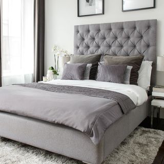 bedroom with grey headboard and rug