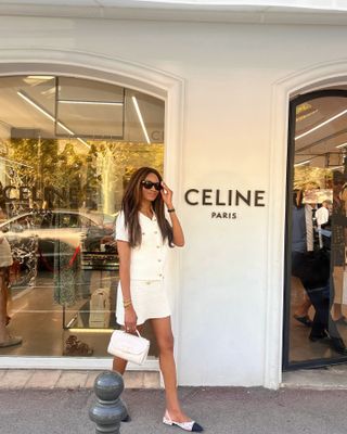 Woman wears a white Chanel tweed Chanel skirt set and cap toe slingbacks.