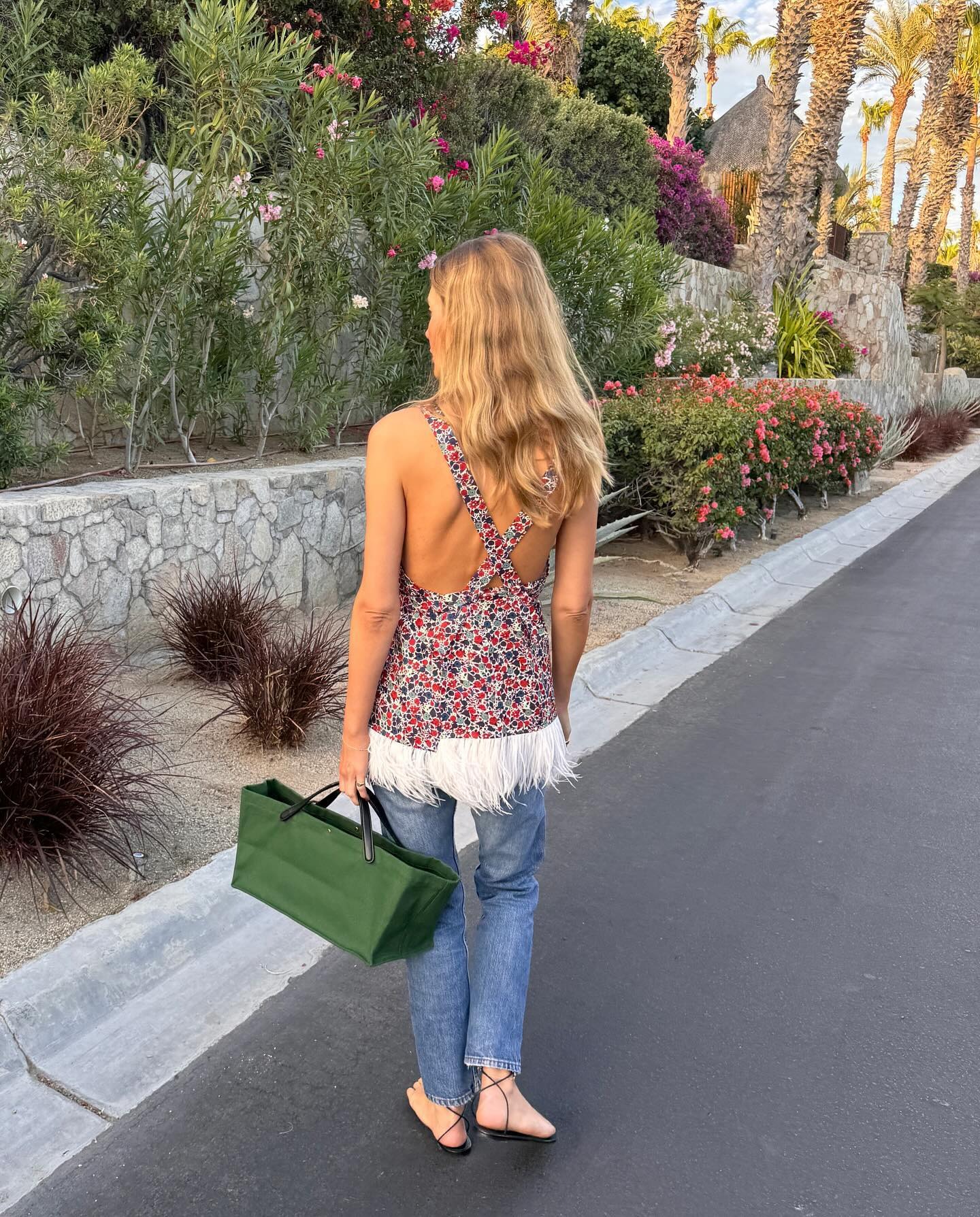 Courtney Grow wearing a printed top, jeans, and a green The Row tote bag.