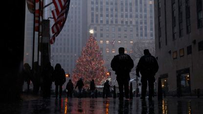 People walk past the Rockefeller Center Christmas tree in New York City. 