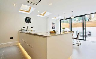 modern white handleless kitchen with large sliding doors and rooflights