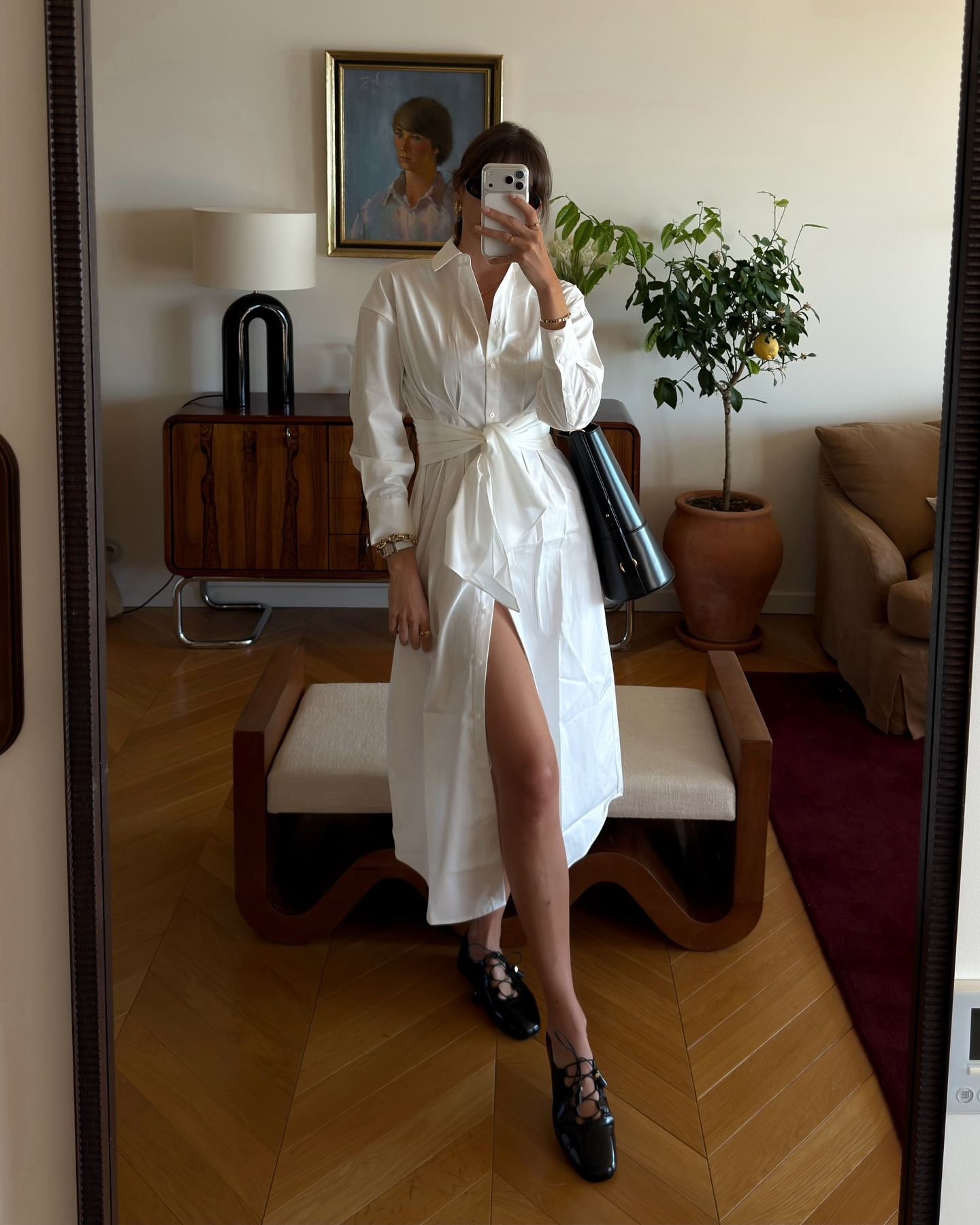 Woman wears white shirt dress and black ballet flats