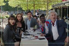 An Emily in Paris still showing Lily Collins as Emily Cooper at a dinner table with other cast members