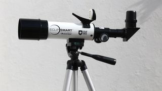 Celestron EclipSmart Travel Solar Scope 50 solar telescope on a tripod in front of a white wall