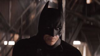 Christian Bale's Batman looking over at Katie Holmes' Rachel Dawes in subway station