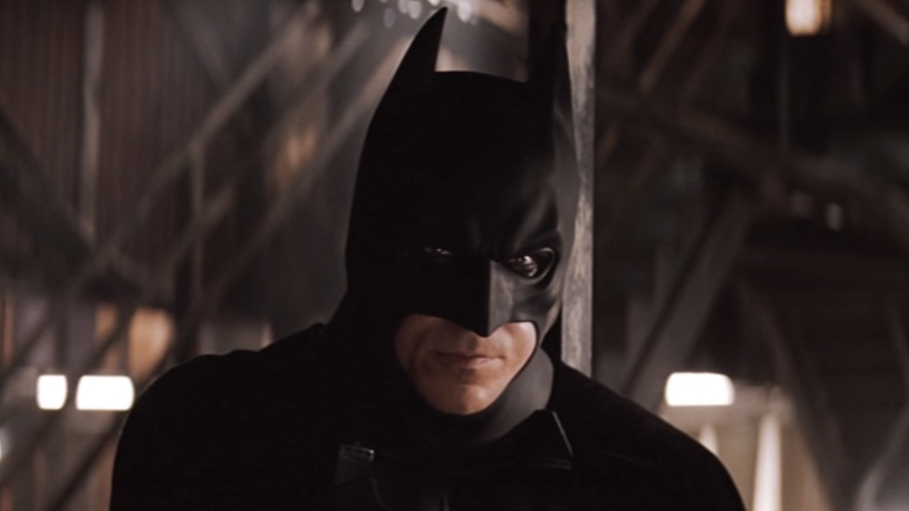 Christian Bale's Batman looking over at Katie Holmes' Rachel Dawes in subway station