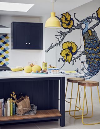 A colorful dark blue kitchen with bar stool island seating and peacock mural