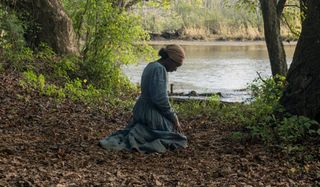 Harriet kneeling in the woods, by the water