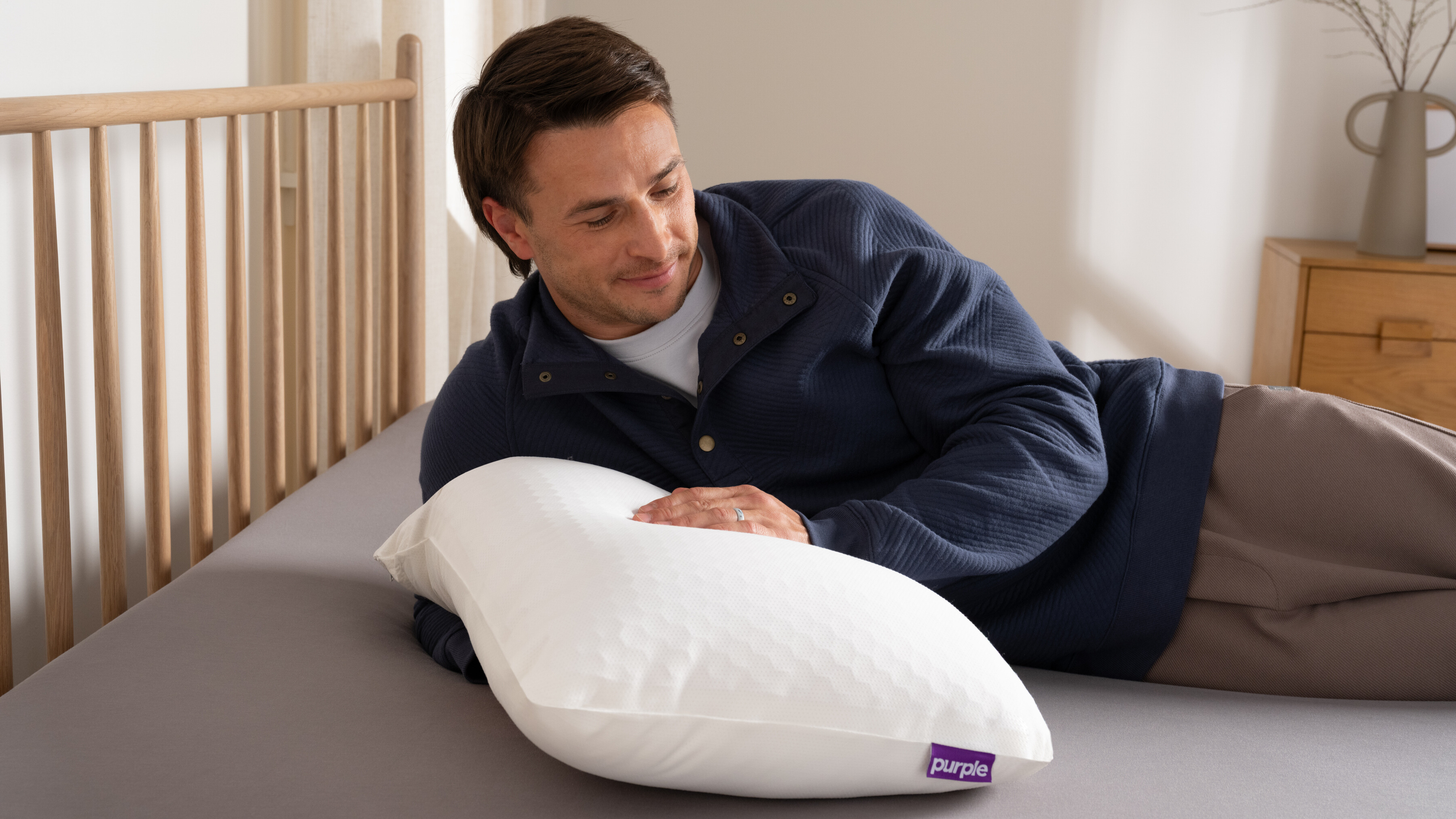 A man resting on the new Purple GridCloud pillow in bed