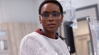 Dr. Collins wears surgical robes and glasses, looking on