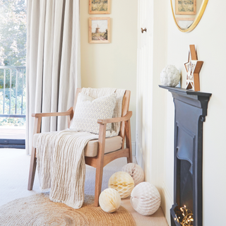 accent chair with cosy throw draped over in in front of a floor length curtain