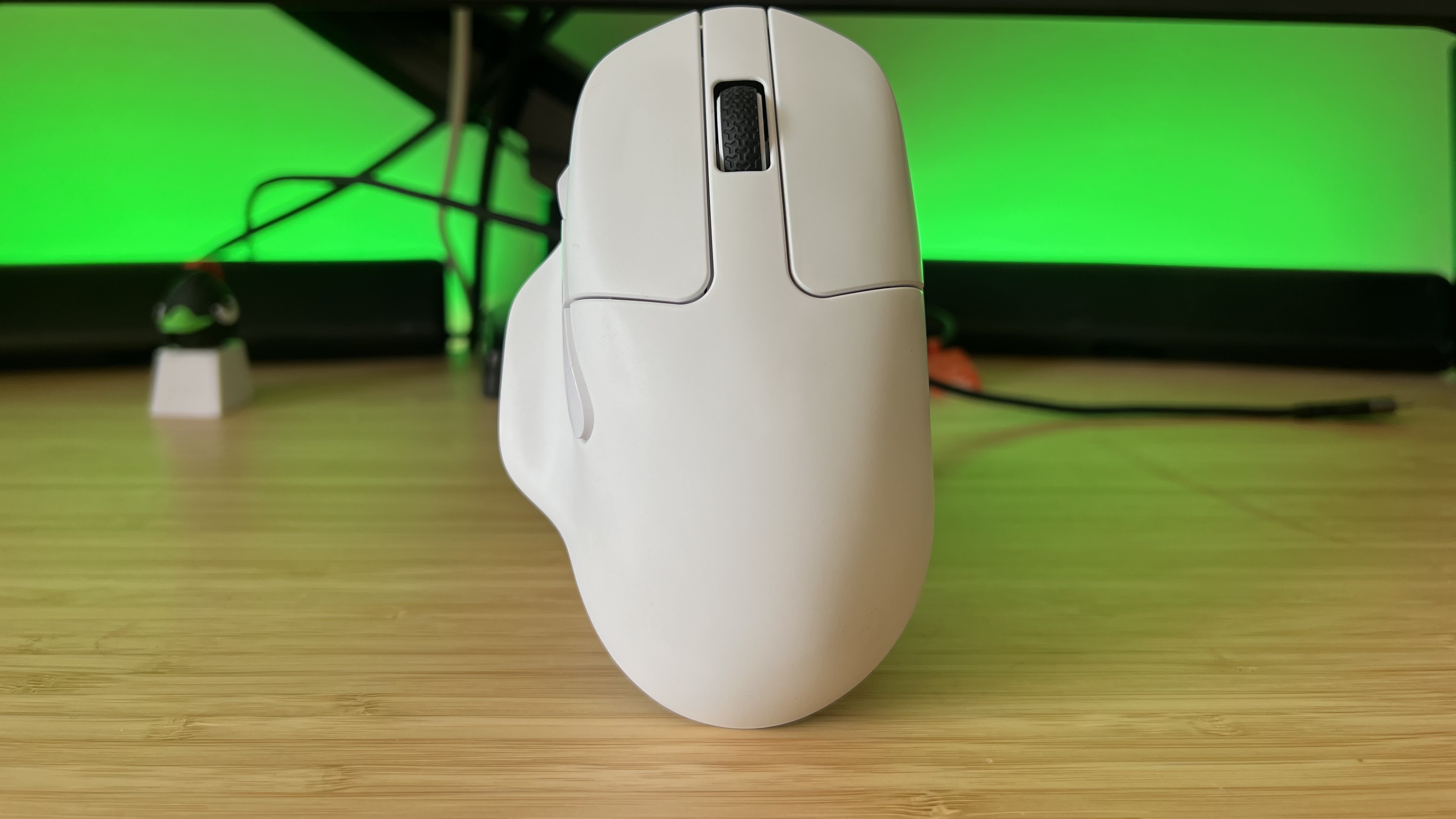 Keychron M7 8K white gaming mouse on a wooden desk with green lighting