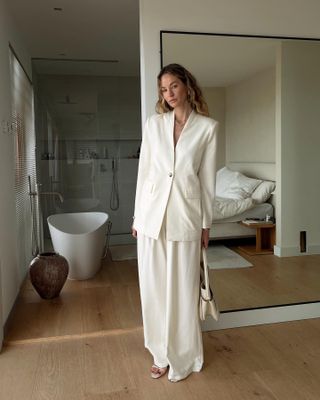 a woman wears a white blazer with matching wide-leg trousers