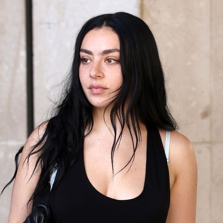 Charli XCX wears a black mini dress with pointed-toe pink crocodile pumps and has long black hair