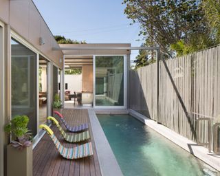 A narrow pool deck area with slimline loungers