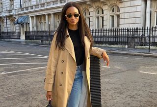 Woman wearing a tan trench coat with jeans and a black tee.