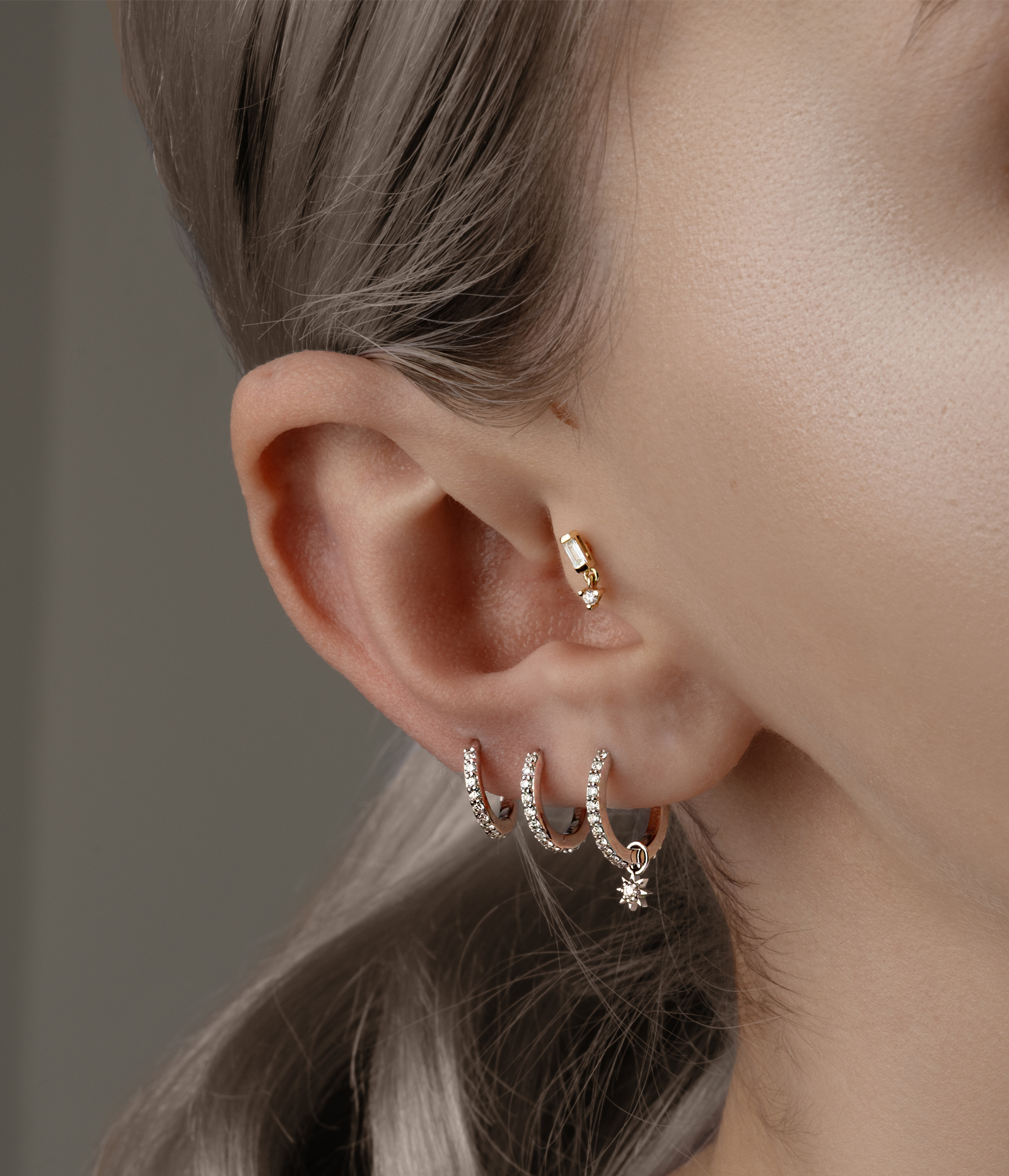 side of woman's face with multiple earrings in ear