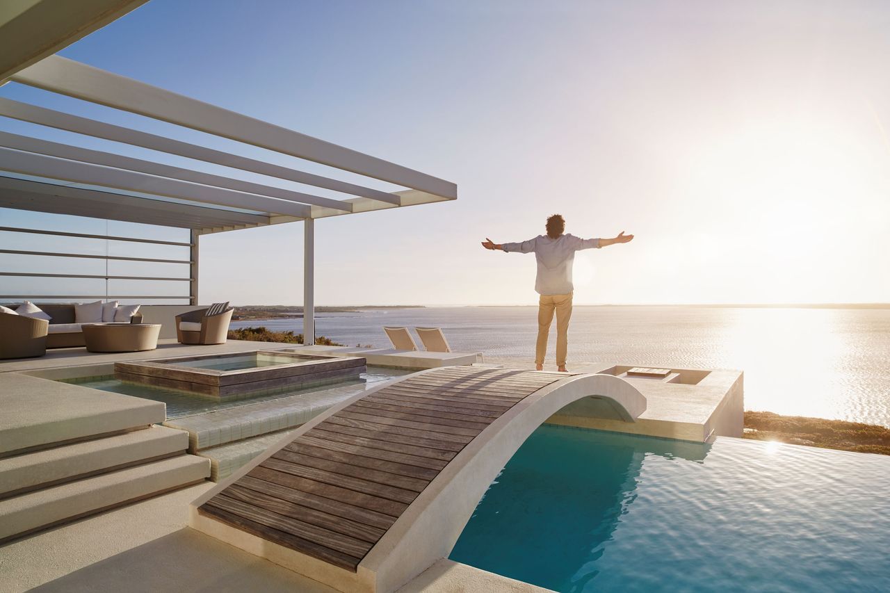 A man stands outside a beautiful vacation rental. 