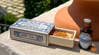 A ceramic matchbox diffuser with a bottle of essential oils on a ledge by a terracotta vase