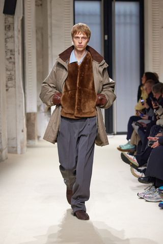 Auralee A/W 2025 runway show at Paris Fashion Week Men’s featuring model in faux fur jacket and coat