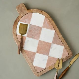 A Magnolia chequered marble chopping board with some utensils around it