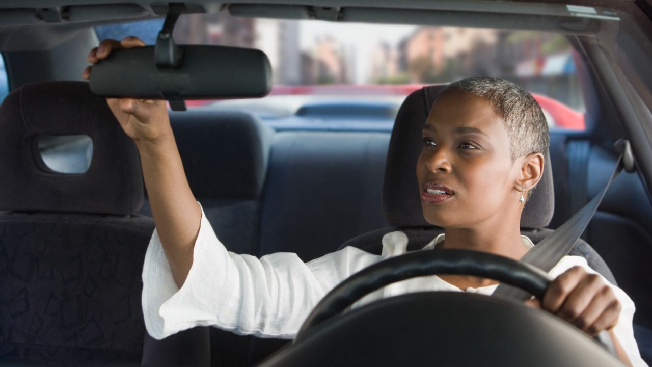 Woman driver adjusted her car mirror