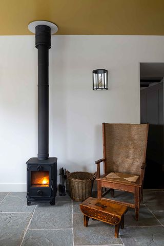 Interiof of the Kinneuchar Inn, Fife, UK with wood burning stove, wicker basket and wooden armchair and footstool