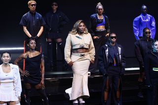 Serena Williams and several Nike athletes stand on a stage wearing Nike sneakers and sports gear