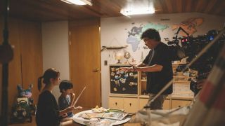 Bong Joon-ho directing the movie Parasite. A man is instructing a woman and young child in a scene in their home.