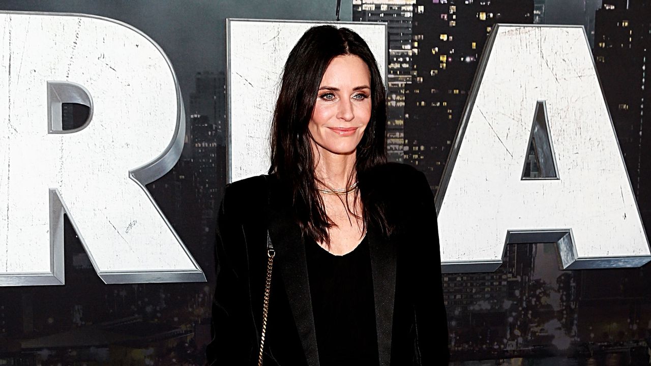 Courteney Cox on red carpet with scream poster in background