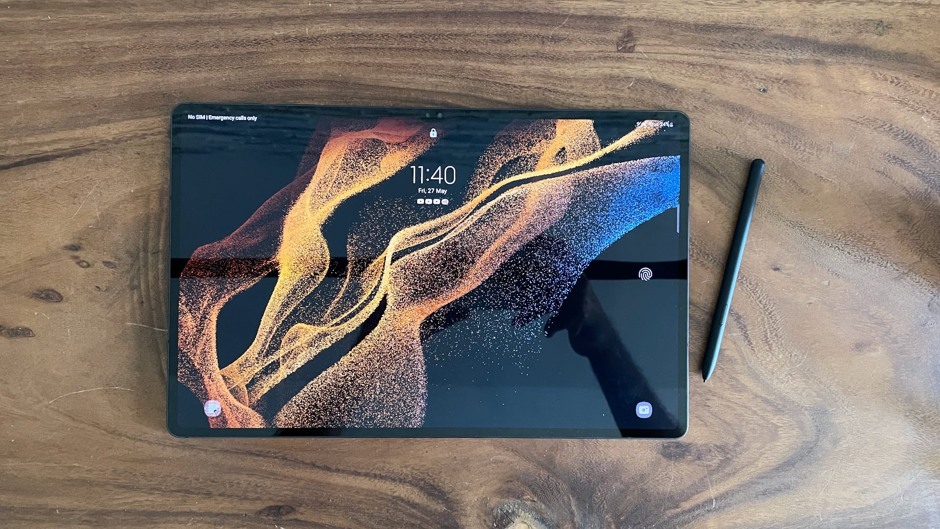 En Samsung Galaxy Tab S8 Ultra ligger på ett träbord med en stylus som ligger bredvid.