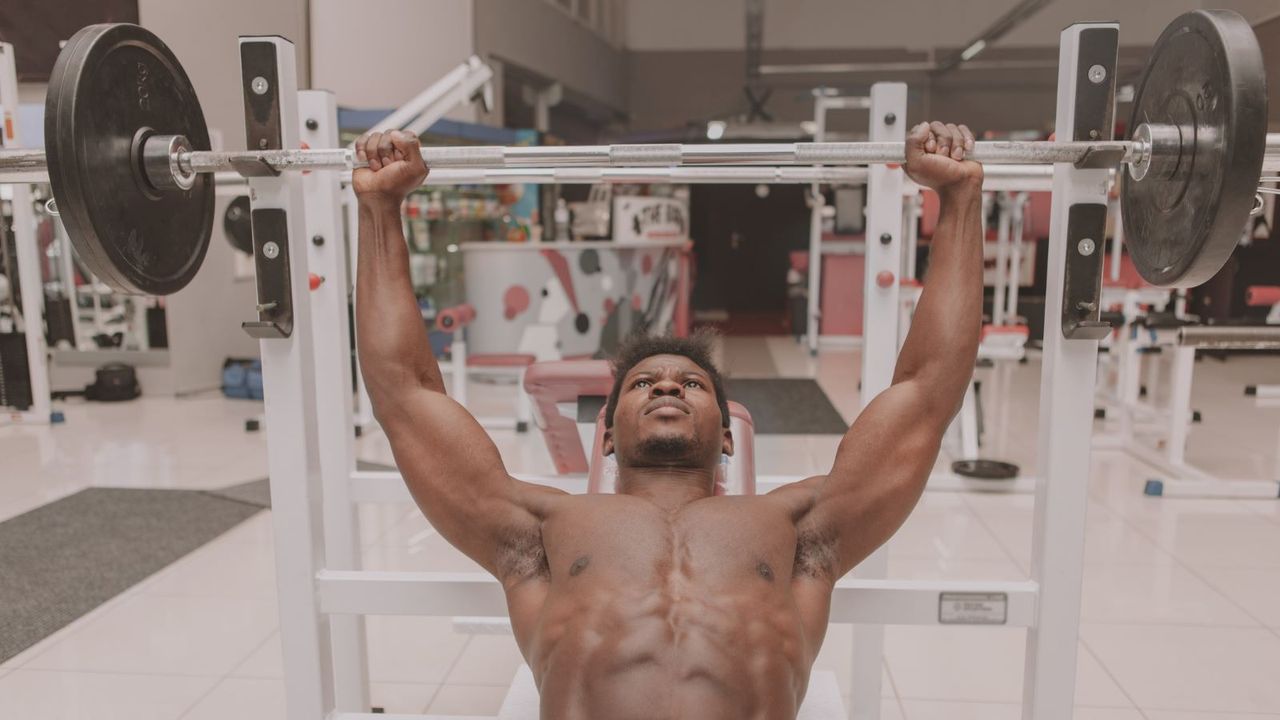 Muscular person bench pressing in a gym