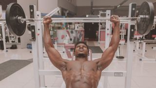 Muscular person using a barbell on a weight bench