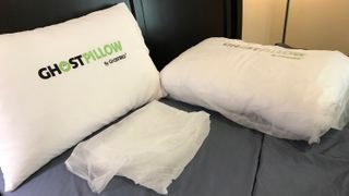 Two GhostBed GhostPillows on a bed, one in its plastic wrapping